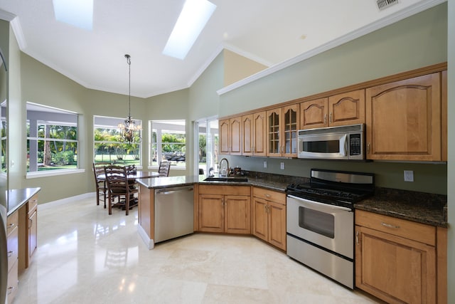 kitchen featuring pendant lighting, sink, appliances with stainless steel finishes, a skylight, and ornamental molding