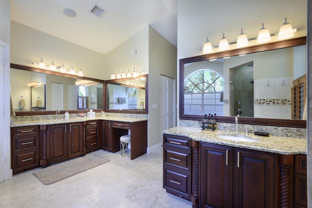 bathroom featuring vaulted ceiling, tiled shower, and vanity