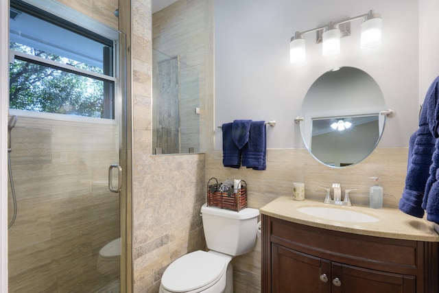 bathroom with a shower with shower door, tasteful backsplash, tile walls, vanity, and toilet