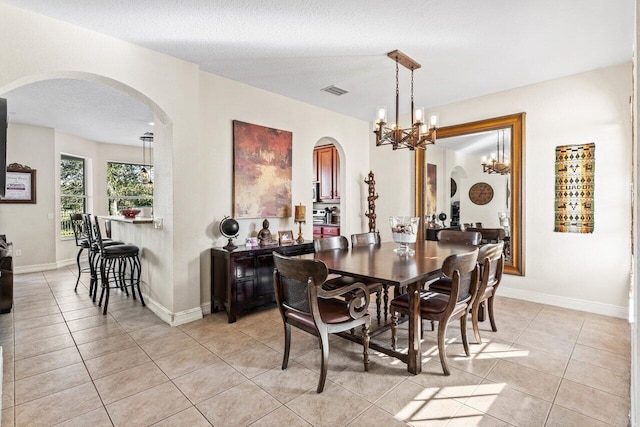 dining space with an inviting chandelier, light tile patterned floors, and a textured ceiling