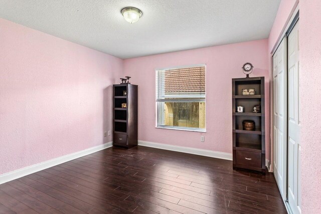 unfurnished bedroom featuring a closet, dark hardwood / wood-style floors, and a textured ceiling