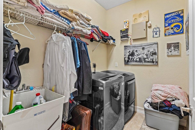 clothes washing area with washing machine and clothes dryer, sink, and light tile patterned floors