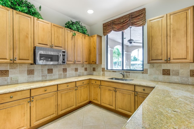 kitchen with sink, light tile patterned floors, ceiling fan, tasteful backsplash, and light stone countertops