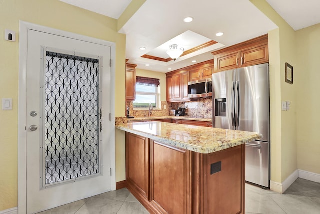 kitchen with sink, appliances with stainless steel finishes, light stone counters, tasteful backsplash, and a tray ceiling