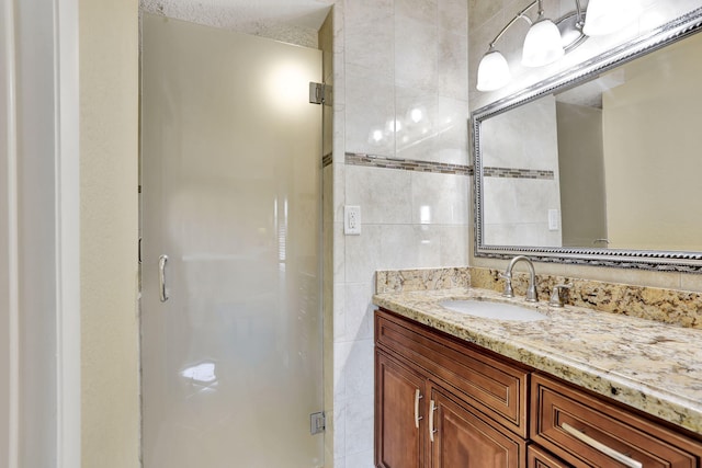 bathroom featuring vanity, tile walls, and a shower with shower door