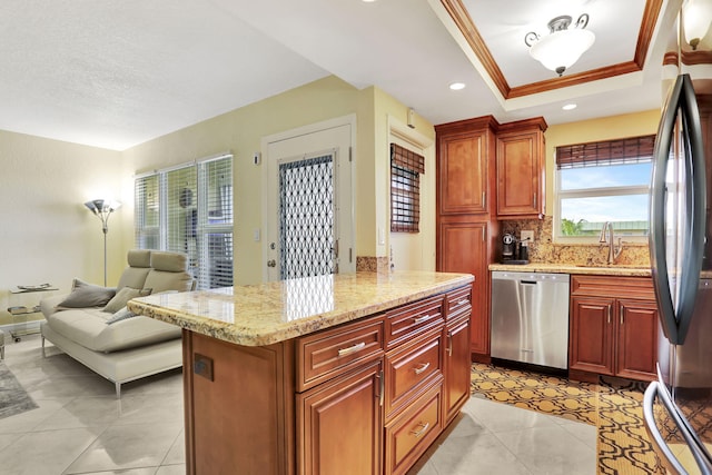 kitchen with sink, tasteful backsplash, a center island, a tray ceiling, and stainless steel appliances