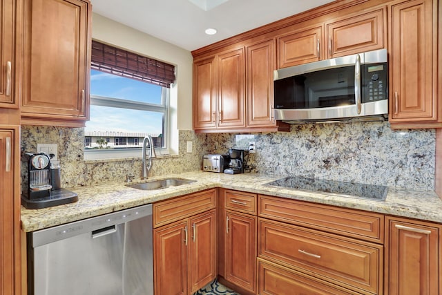 kitchen with sink, backsplash, light stone countertops, and appliances with stainless steel finishes