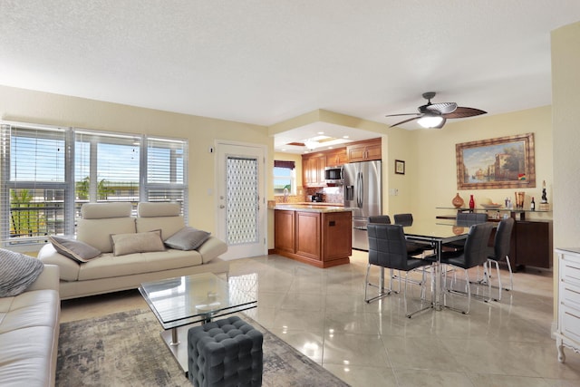 living room featuring ceiling fan and a textured ceiling