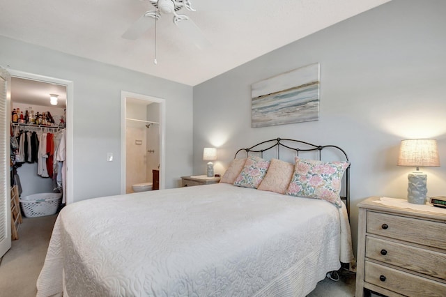 carpeted bedroom featuring ensuite bathroom, a spacious closet, a closet, and a ceiling fan