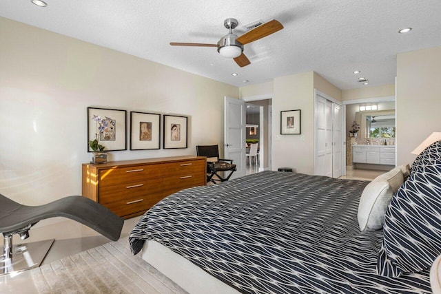 bedroom with connected bathroom, a textured ceiling, and ceiling fan