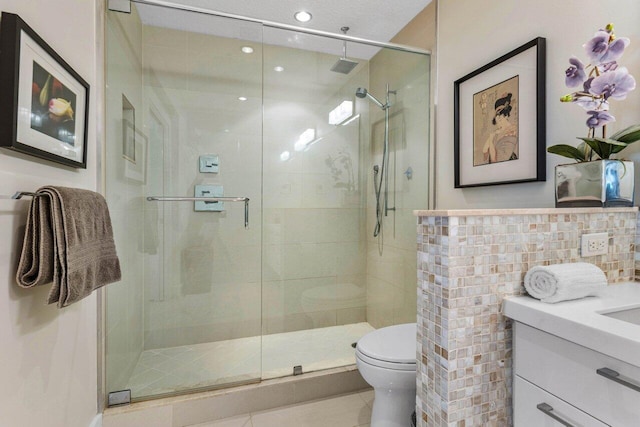 bathroom with an enclosed shower, vanity, tile walls, and toilet