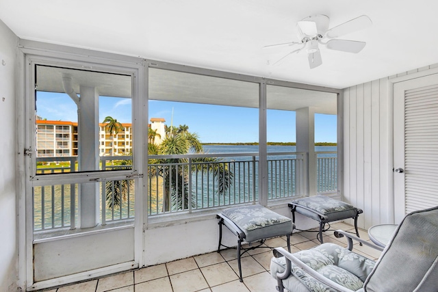 sunroom / solarium with plenty of natural light, ceiling fan, and a water view