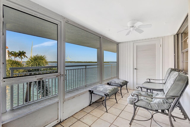 sunroom with a healthy amount of sunlight, ceiling fan, and a water view