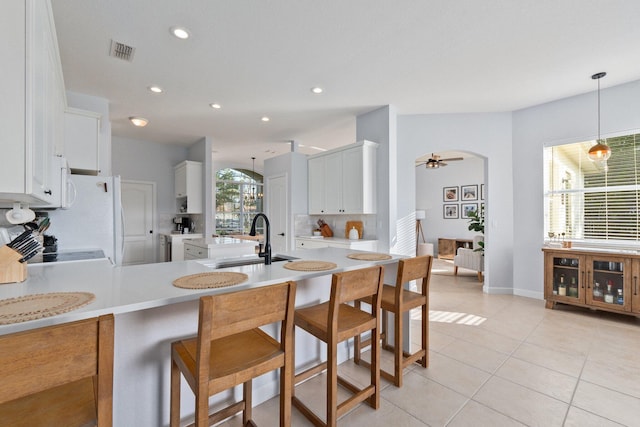 kitchen featuring sink, light tile patterned floors, white cabinetry, decorative light fixtures, and kitchen peninsula