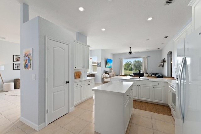 kitchen with sink, white cabinetry, a center island, kitchen peninsula, and white appliances