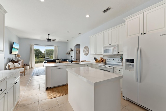 kitchen featuring white appliances, kitchen peninsula, sink, and a kitchen island