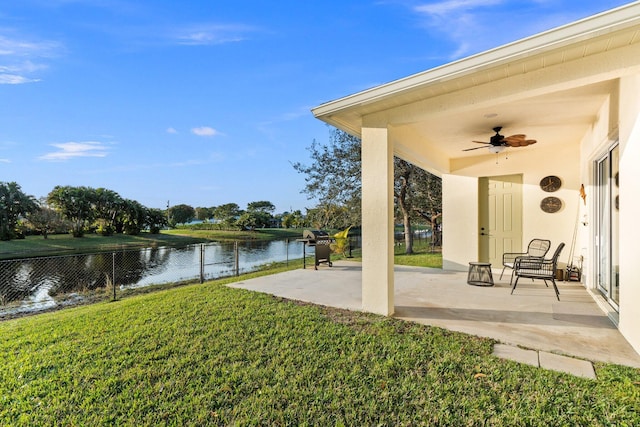 view of yard featuring a water view, ceiling fan, and a patio