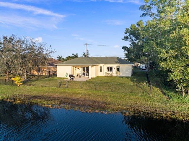 rear view of house with a patio area, a lawn, and a water view