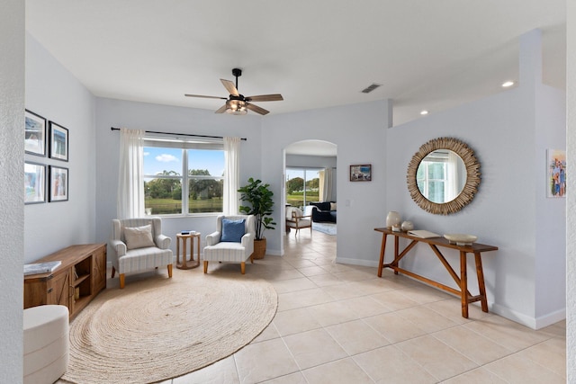 living area with light tile patterned floors and ceiling fan