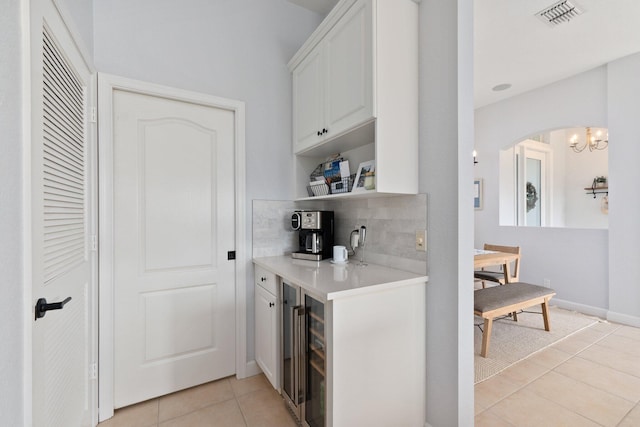 kitchen featuring light tile patterned flooring, beverage cooler, white cabinets, and backsplash