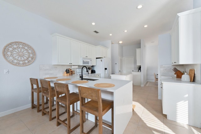 kitchen with sink, white appliances, white cabinetry, a kitchen breakfast bar, and kitchen peninsula