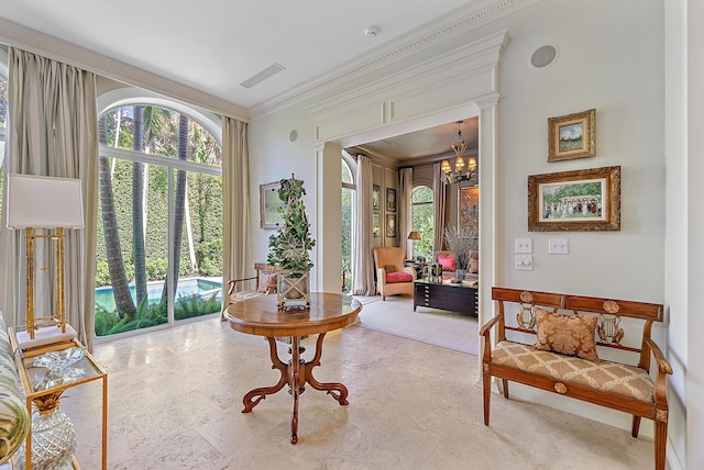 sitting room with decorative columns, crown molding, and a chandelier