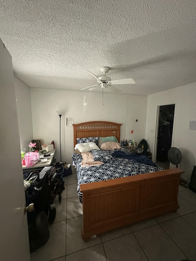 tiled bedroom with ceiling fan and a textured ceiling