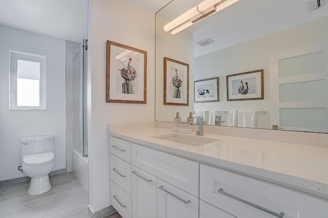 full bathroom featuring vanity, enclosed tub / shower combo, and toilet