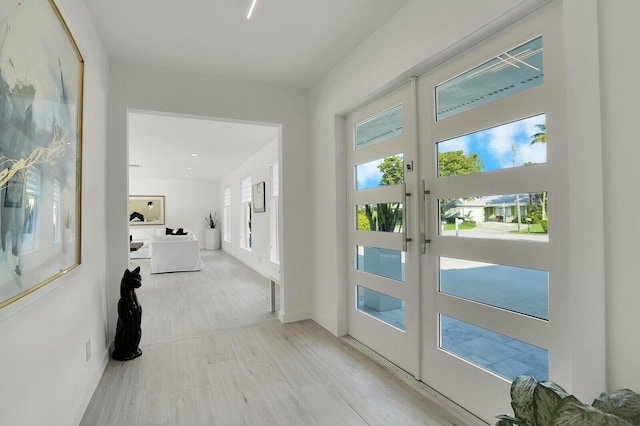 hall with light hardwood / wood-style flooring and french doors