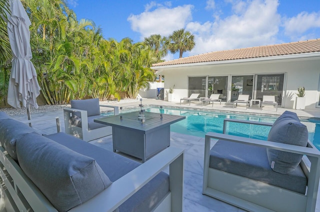 view of pool featuring an outdoor living space with a fire pit and a patio area