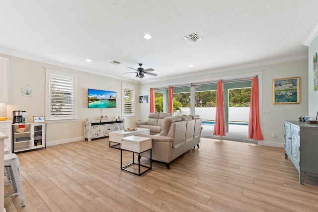 living room with ceiling fan, ornamental molding, a textured ceiling, and light wood-type flooring