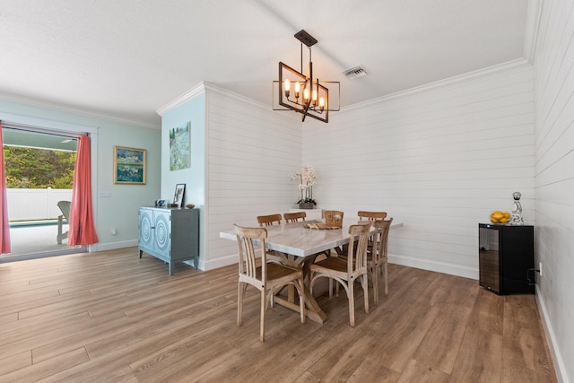 dining area with a notable chandelier, hardwood / wood-style flooring, and ornamental molding