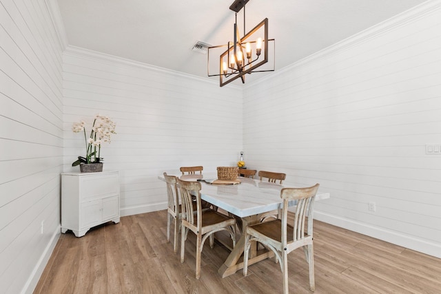 dining area featuring a notable chandelier, ornamental molding, and light wood-type flooring