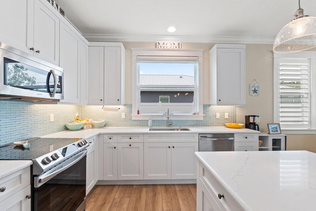 kitchen with sink, crown molding, appliances with stainless steel finishes, hanging light fixtures, and white cabinets