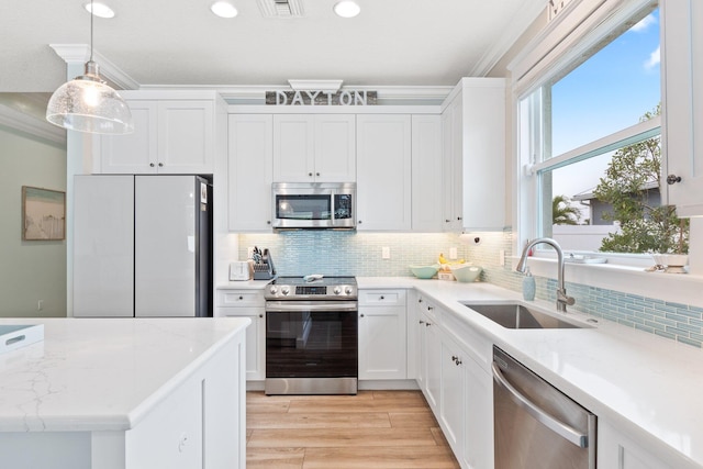 kitchen featuring pendant lighting, stainless steel appliances, sink, and white cabinets