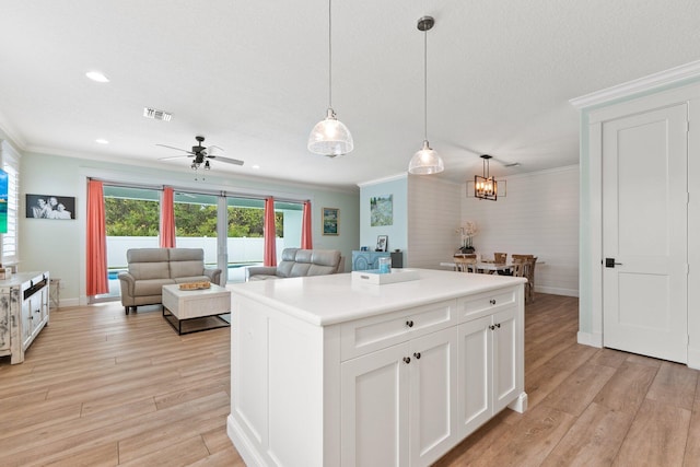 kitchen with white cabinetry, ornamental molding, and pendant lighting