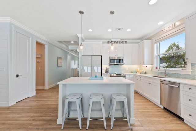 kitchen featuring sink, white cabinetry, hanging light fixtures, a kitchen island, and stainless steel appliances