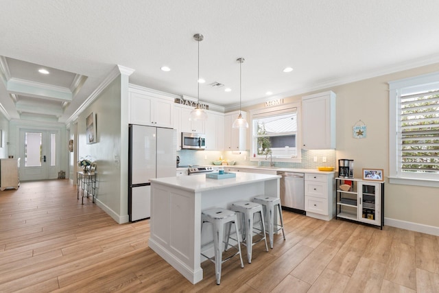 kitchen featuring a breakfast bar, white cabinetry, hanging light fixtures, appliances with stainless steel finishes, and a kitchen island