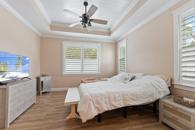 bedroom with a tray ceiling, ornamental molding, light hardwood / wood-style floors, and ceiling fan