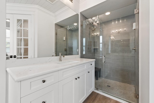 bathroom with ornamental molding, hardwood / wood-style floors, an enclosed shower, and vanity