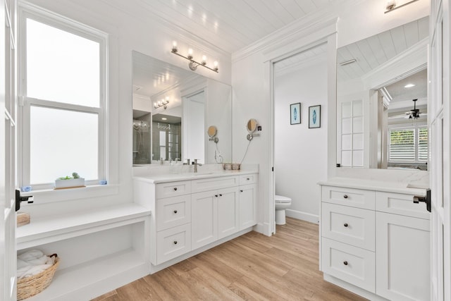 bathroom with toilet, ornamental molding, vanity, ceiling fan, and hardwood / wood-style floors