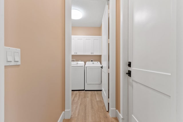 clothes washing area with cabinets, washing machine and dryer, a textured ceiling, and light hardwood / wood-style flooring