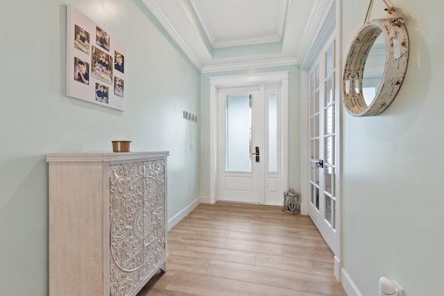 entryway featuring ornamental molding, a raised ceiling, and light hardwood / wood-style flooring