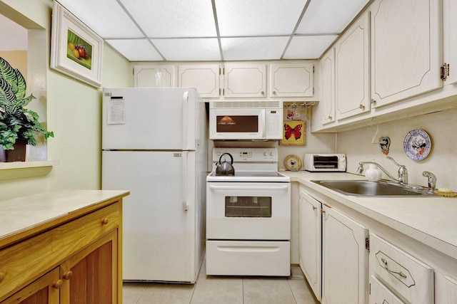 kitchen with sink, white cabinetry, a paneled ceiling, light tile patterned floors, and white appliances