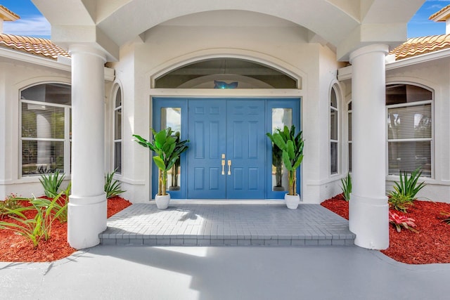 property entrance featuring a tiled roof and stucco siding