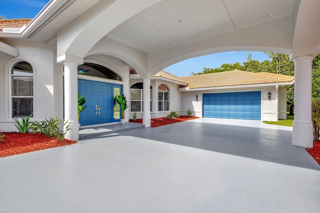 view of front of home with a garage, a tile roof, and stucco siding