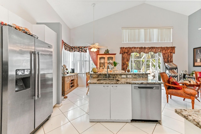 kitchen with sink, white cabinetry, light tile patterned floors, stainless steel appliances, and light stone countertops