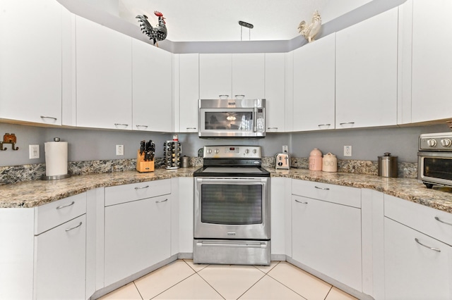 kitchen featuring light stone countertops, light tile patterned flooring, appliances with stainless steel finishes, and white cabinets