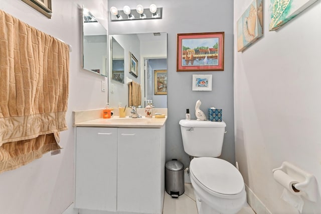 bathroom with toilet, vanity, and baseboards