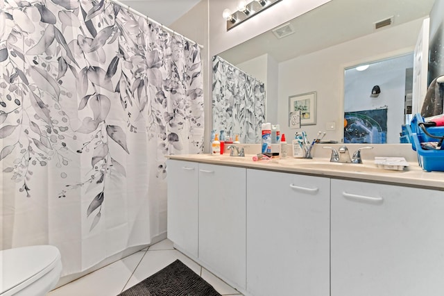 bathroom with a sink, tile patterned floors, toilet, and double vanity